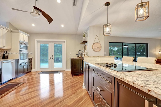 18366 Lake Bend Dr, Jupiter, FL 33458 - kitchen featuring appliances with stainless steel finishes, ceiling fan, french doors, light wood finished floors, and pendant lighting
