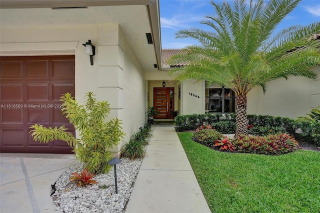 18366 Lake Bend Dr, Jupiter, FL 33458 - view of exterior entry with stucco siding and a garage
