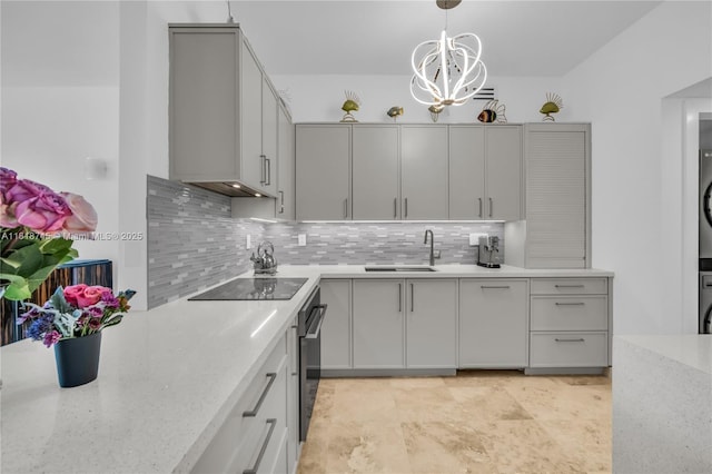 400 Alton Rd Unit 407, Miami Beach, FL 33139 - kitchen featuring stacked washer and clothes dryer, black electric cooktop, gray cabinetry, tasteful backsplash, and decorative light fixtures