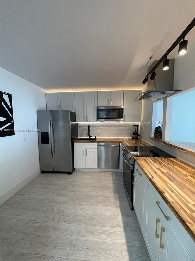 2801 NE 183rd St Unit 1611W, Aventura, FL 33160 - kitchen featuring stainless steel appliances, butcher block countertops, decorative backsplash, light wood-type flooring, and a sink