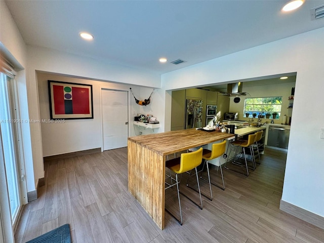 7650 SW 78th Ct, Miami, FL 33143 - kitchen featuring stainless steel appliances, butcher block countertops, light wood-type flooring, recessed lighting, and a breakfast bar area