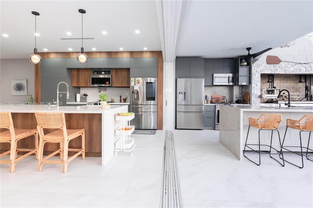 1828 Aspen Ln, Weston, FL 33327 - kitchen with appliances with stainless steel finishes, modern cabinets, a kitchen bar, light countertops, and decorative backsplash