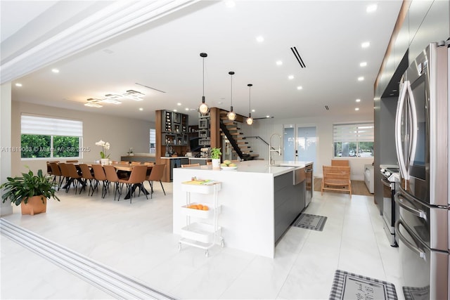 1828 Aspen Ln, Weston, FL 33327 - kitchen featuring appliances with stainless steel finishes, a large island with sink, modern cabinets, light countertops, and hanging light fixtures