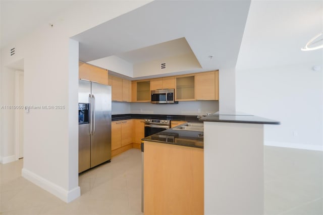 16699 Collins Ave Unit 2107, Sunny Isles Beach, FL 33160 - kitchen featuring stainless steel appliances, dark countertops, light brown cabinets, a peninsula, and a tray ceiling