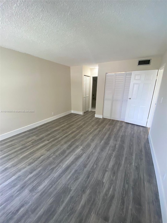 2935 NE 163rd St Unit 3P, North Miami Beach, FL 33160 - unfurnished bedroom featuring dark wood finished floors, a textured ceiling, and two closets