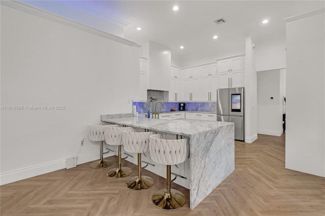 5478 SW 189th Ave, Miramar, FL 33029 - kitchen with smart refrigerator, a peninsula, white cabinets, a breakfast bar, and tasteful backsplash