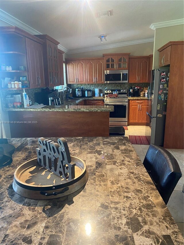 12780 SW 187th St, Miami, FL 33177 - kitchen with appliances with stainless steel finishes, crown molding, decorative backsplash, glass insert cabinets, and dark stone counters