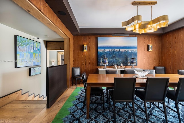 dining space featuring light wood-type flooring and wooden walls