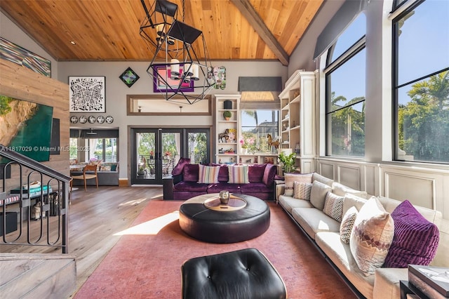 living room with a wooden ceiling with exposed beams, wood finished floors, high vaulted ceiling, and french doors