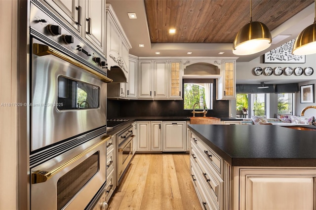 kitchen with dark countertops, stainless steel oven, light wood-style floors, a tray ceiling, and decorative backsplash