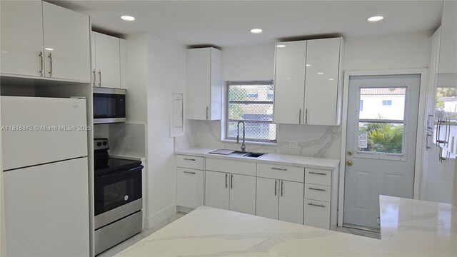 130 W 60th St, Hialeah, FL 33012 - kitchen featuring appliances with stainless steel finishes, a sink, white cabinetry, recessed lighting, and healthy amount of natural light