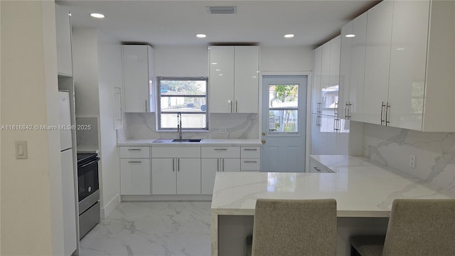 130 W 60th St, Hialeah, FL 33012 - kitchen with a sink, modern cabinets, a peninsula, white cabinetry, and light marble finish flooring