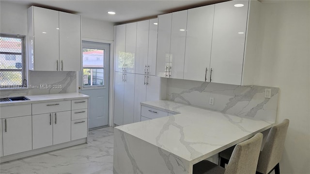 130 W 60th St, Hialeah, FL 33012 - kitchen featuring light marble finish flooring, white cabinetry, light stone countertops, decorative backsplash, and modern cabinets