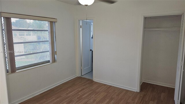 130 W 60th St, Hialeah, FL 33012 - unfurnished bedroom with wood finished floors, multiple windows, a closet, and baseboards