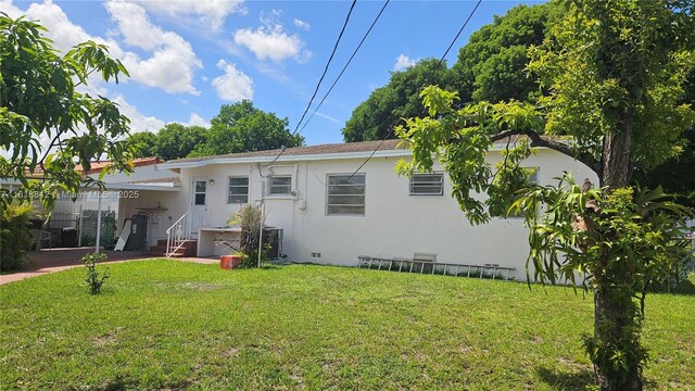 130 W 60th St, Hialeah, FL 33012 - back of property featuring a yard, stucco siding, a carport, and crawl space