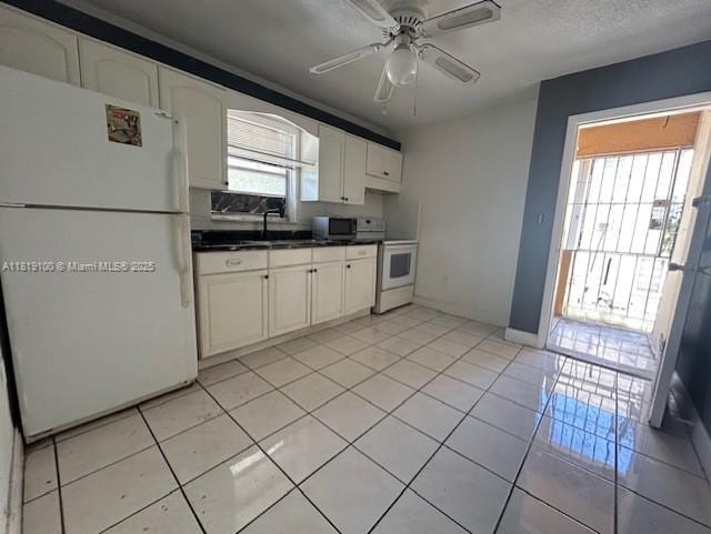 515 SW 3rd St Unit 12, Miami, FL 33130 - kitchen featuring white appliances, dark countertops, a ceiling fan, white cabinets, and light tile patterned floors