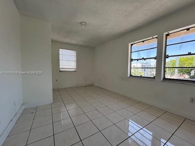 515 SW 3rd St Unit 12, Miami, FL 33130 - empty room featuring a textured ceiling, light tile patterned flooring, and baseboards