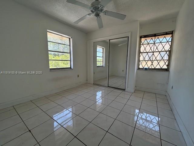 515 SW 3rd St Unit 12, Miami, FL 33130 - unfurnished bedroom with a textured ceiling, a closet, baseboards, light tile patterned floors, and ceiling fan