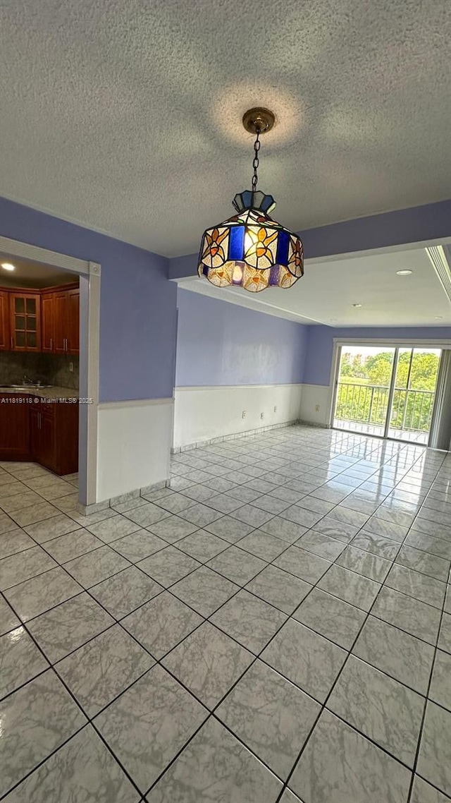9455 W Flagler St Unit C308, Miami, FL 33174 - unfurnished dining area with a textured ceiling and a wainscoted wall