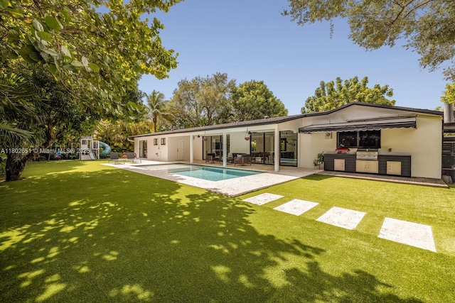 7921 SW 100th St, Miami, FL 33156 - back of property with area for grilling, a patio, an outdoor pool, a lawn, and stucco siding