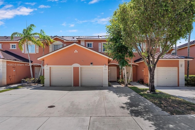 1114 NW 100th Ave, Pembroke Pines, FL 33024 - townhome / multi-family property with stucco siding, a standing seam roof, concrete driveway, a metal roof, and an attached garage