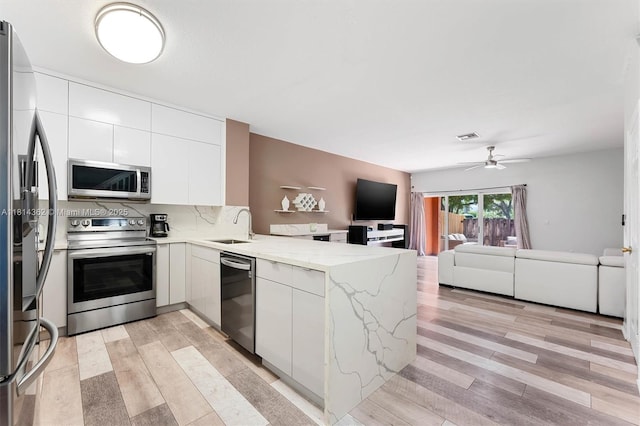 1114 NW 100th Ave, Pembroke Pines, FL 33024 - kitchen featuring appliances with stainless steel finishes, a peninsula, open floor plan, white cabinets, and light stone counters