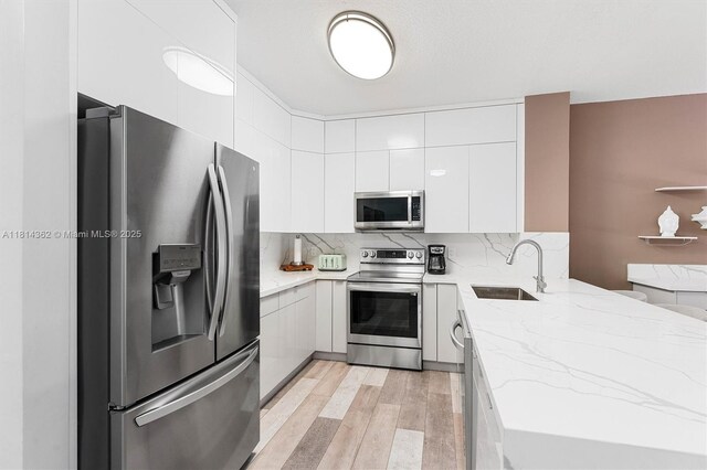 1114 NW 100th Ave, Pembroke Pines, FL 33024 - kitchen featuring stainless steel appliances, light wood-style floors, white cabinetry, light stone countertops, and backsplash