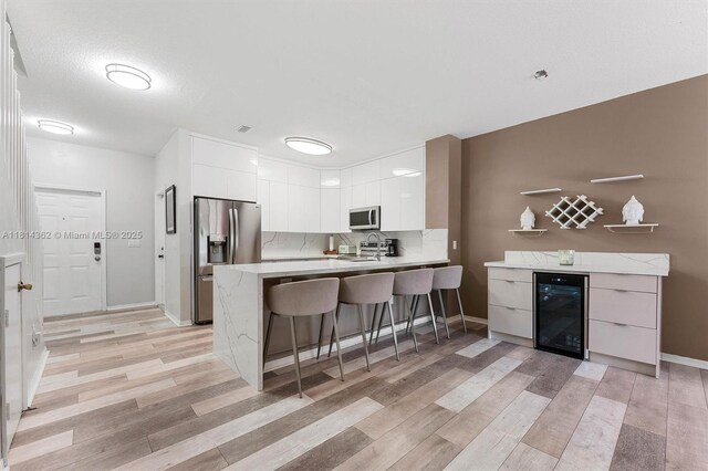 1114 NW 100th Ave, Pembroke Pines, FL 33024 - kitchen featuring wine cooler, appliances with stainless steel finishes, modern cabinets, a peninsula, and white cabinets