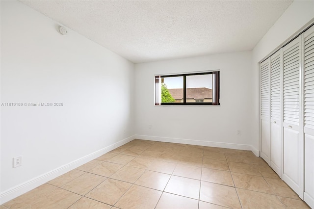 1121 SW 105th Ave Unit 302, Miami, FL 33174 - unfurnished bedroom with a textured ceiling, a closet, light tile patterned floors, and baseboards