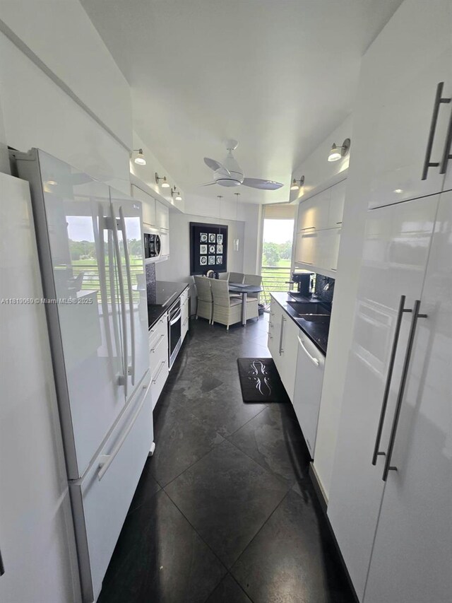 7400 Radice Ct Unit 402, Lauderhill, FL 33319 - kitchen with appliances with stainless steel finishes, dark countertops, white cabinetry, ceiling fan, and modern cabinets