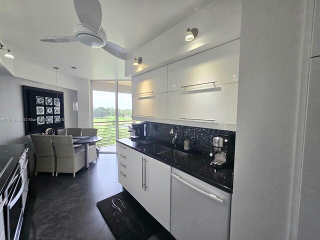 7400 Radice Ct Unit 402, Lauderhill, FL 33319 - kitchen featuring white dishwasher, a sink, dark countertops, white cabinetry, and decorative backsplash