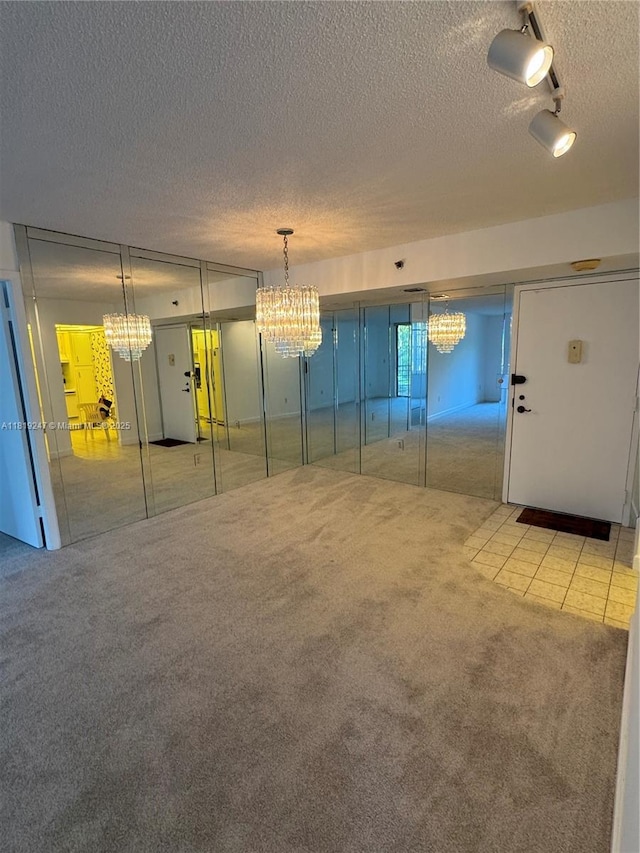 1100 Saint Charles Pl Unit 203, Pembroke Pines, FL 33026 - unfurnished living room with carpet, a chandelier, a textured ceiling, rail lighting, and tile patterned flooring