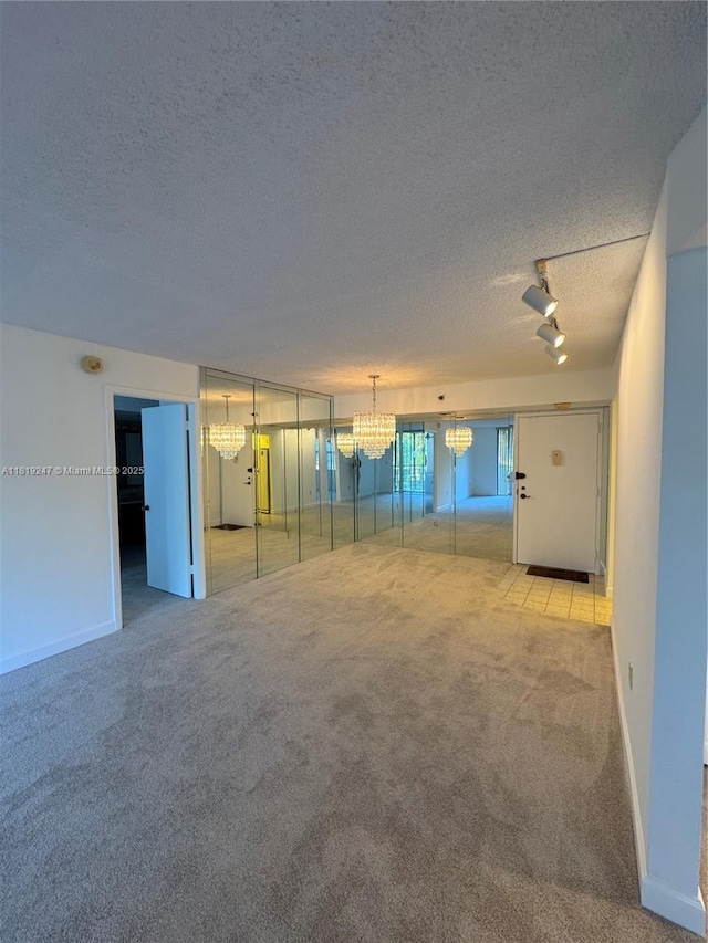 1100 Saint Charles Pl Unit 203, Pembroke Pines, FL 33026 - unfurnished living room featuring carpet floors, a textured ceiling, a chandelier, track lighting, and baseboards