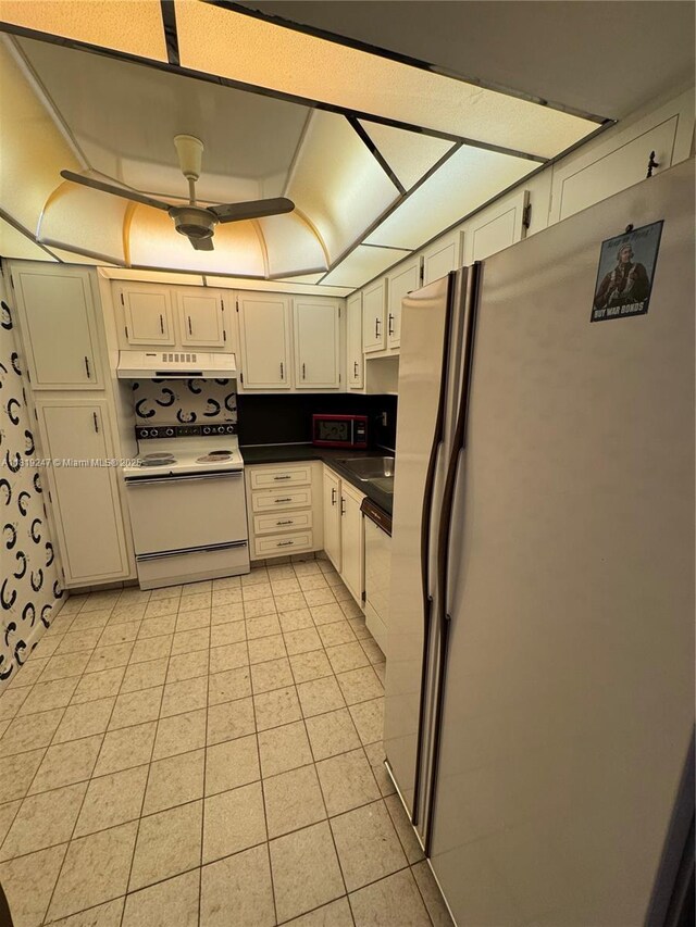 1100 Saint Charles Pl Unit 203, Pembroke Pines, FL 33026 - kitchen featuring white appliances, dark countertops, under cabinet range hood, and light tile patterned floors