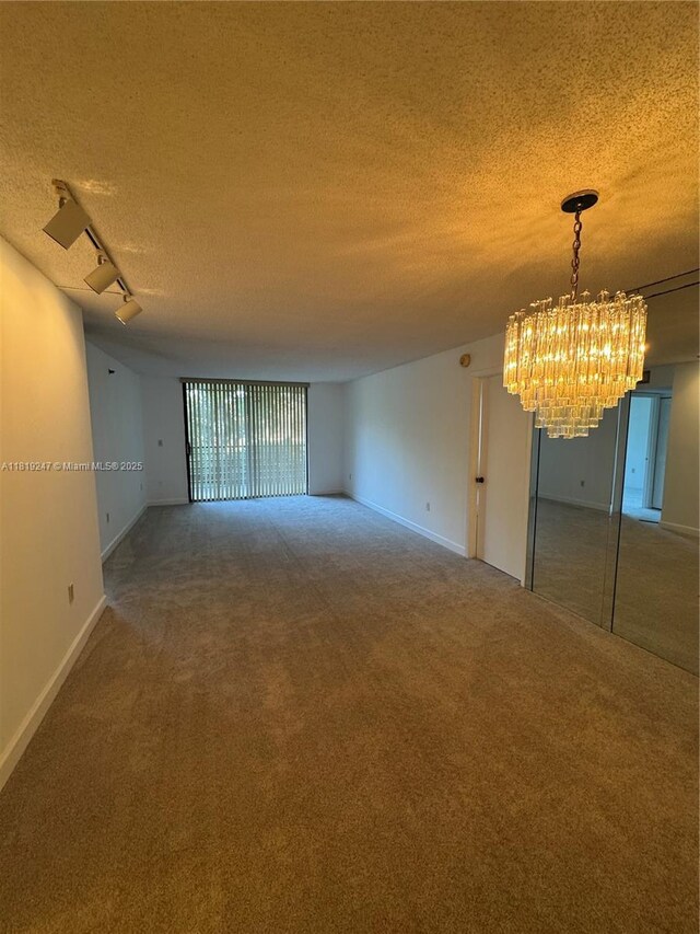1100 Saint Charles Pl Unit 203, Pembroke Pines, FL 33026 - carpeted empty room with a chandelier, a textured ceiling, baseboards, and rail lighting
