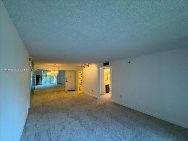 1100 Saint Charles Pl Unit 203, Pembroke Pines, FL 33026 - unfurnished living room featuring a chandelier, light carpet, a textured ceiling, and baseboards