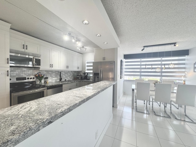 2741 Taft St Unit 410, Hollywood, FL 33020 - kitchen with appliances with stainless steel finishes, light tile patterned floors, light stone counters, backsplash, and rail lighting