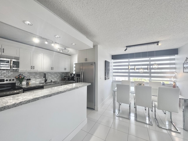 2741 Taft St Unit 410, Hollywood, FL 33020 - kitchen with appliances with stainless steel finishes, rail lighting, backsplash, light stone counters, and a textured ceiling
