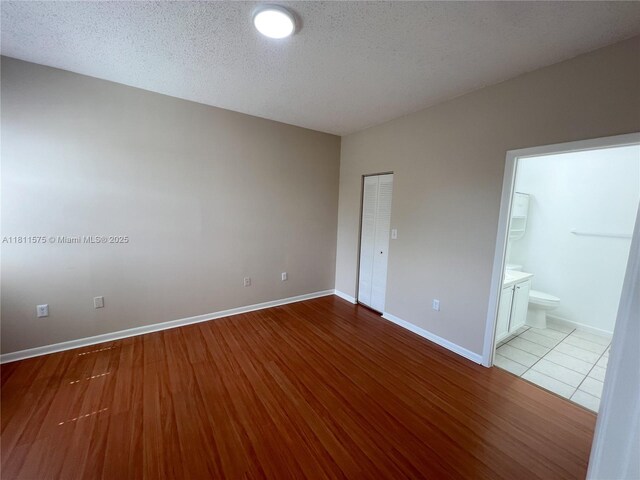 1881 NW 96th Ter Unit 7C, Pembroke Pines, FL 33024 - unfurnished bedroom featuring wood finished floors, ensuite bath, a closet, and a textured ceiling