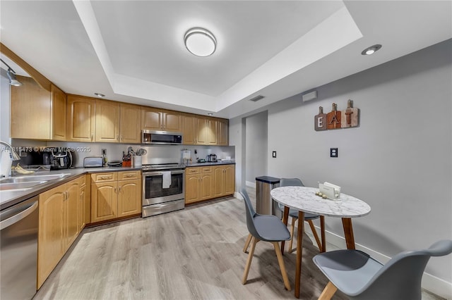 8331 NW 18th St, Pembroke Pines, FL 33024 - kitchen featuring appliances with stainless steel finishes, a raised ceiling, dark countertops, light wood-style floors, and recessed lighting