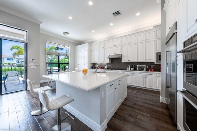 9368 Eden Roc Ct, Delray Beach, FL 33446 - kitchen with crown molding, built in appliances, dark wood-style flooring, white cabinets, and light countertops