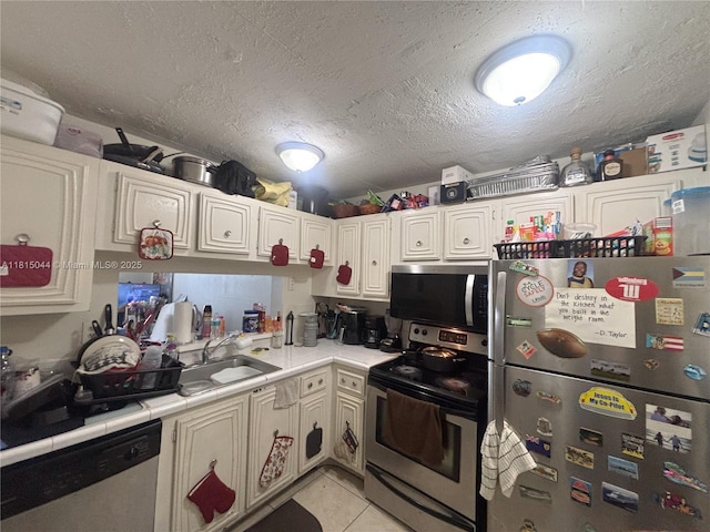 498 NW 165th St Rd Unit D-405, Miami, FL 33169 - kitchen featuring stainless steel appliances, light tile patterned flooring, tile counters, a textured ceiling, and a sink