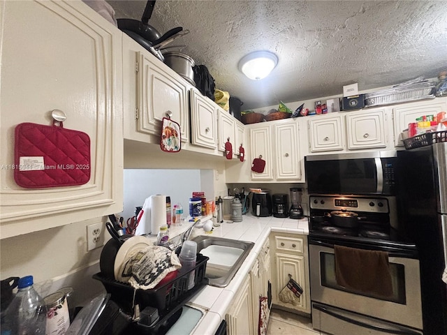 498 NW 165th St Rd Unit D-405, Miami, FL 33169 - kitchen featuring tile counters, stainless steel appliances, a sink, and a textured ceiling
