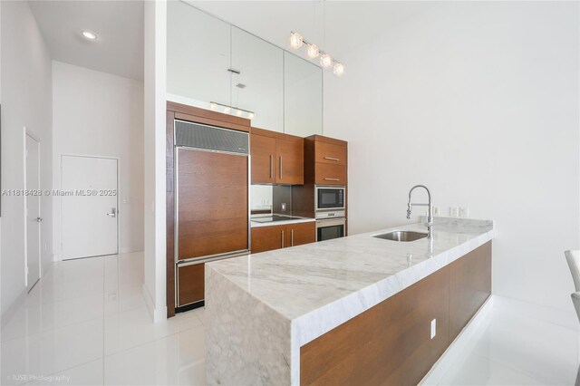 475 Brickell Ave Unit 2807, Miami, FL 33131 - kitchen with a sink, built in appliances, a peninsula, brown cabinets, and light stone counters
