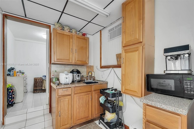 1150 W 69th Pl, Hialeah, FL 33014 - kitchen featuring black microwave, light tile patterned flooring, light countertops, a sink, and tasteful backsplash