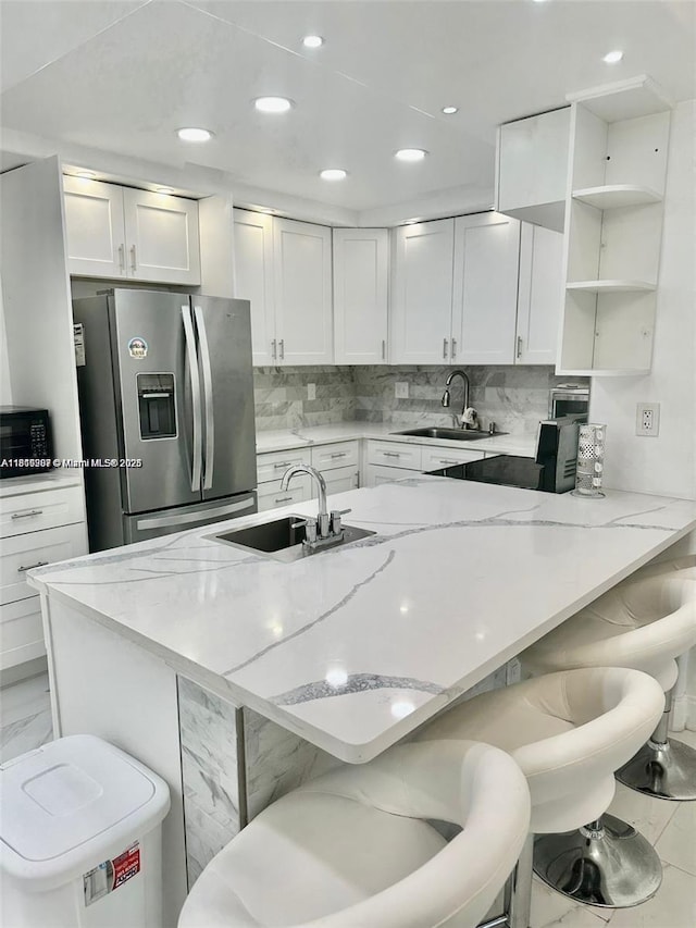 600 Three Islands Blvd Unit 703, Hallandale Beach, FL 33009 - kitchen featuring stainless steel refrigerator with ice dispenser, a sink, a breakfast bar, white cabinetry, and recessed lighting
