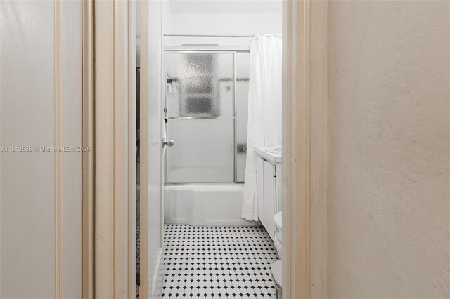 7280 SW 9th St, Miami, FL 33144 - bathroom featuring vanity, shower / bath combination with glass door, toilet, a textured wall, and tile patterned floors