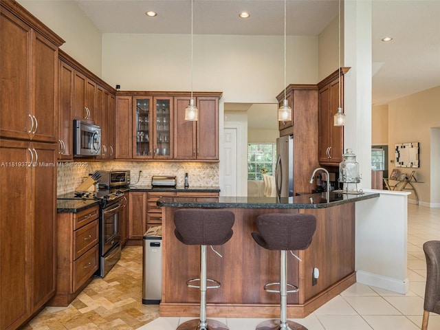 643 Lake Blvd, Weston, FL 33326 - kitchen featuring appliances with stainless steel finishes, a peninsula, glass insert cabinets, a breakfast bar, and dark stone counters