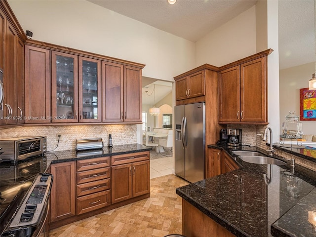 643 Lake Blvd, Weston, FL 33326 - kitchen featuring stainless steel refrigerator with ice dispenser, a sink, decorative backsplash, dark stone countertops, and glass insert cabinets