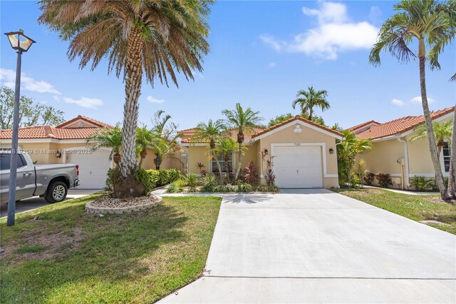 7182 Burgess Dr, Lake Worth, FL 33467 - mediterranean / spanish-style home with a garage, concrete driveway, stucco siding, a front lawn, and a tile roof